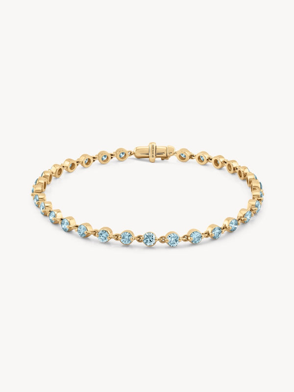 Gold bracelet with aquamarine gemstones on a white background